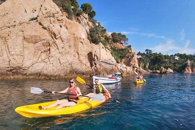 people practicing outdoor activities like kayaking at blanes sea